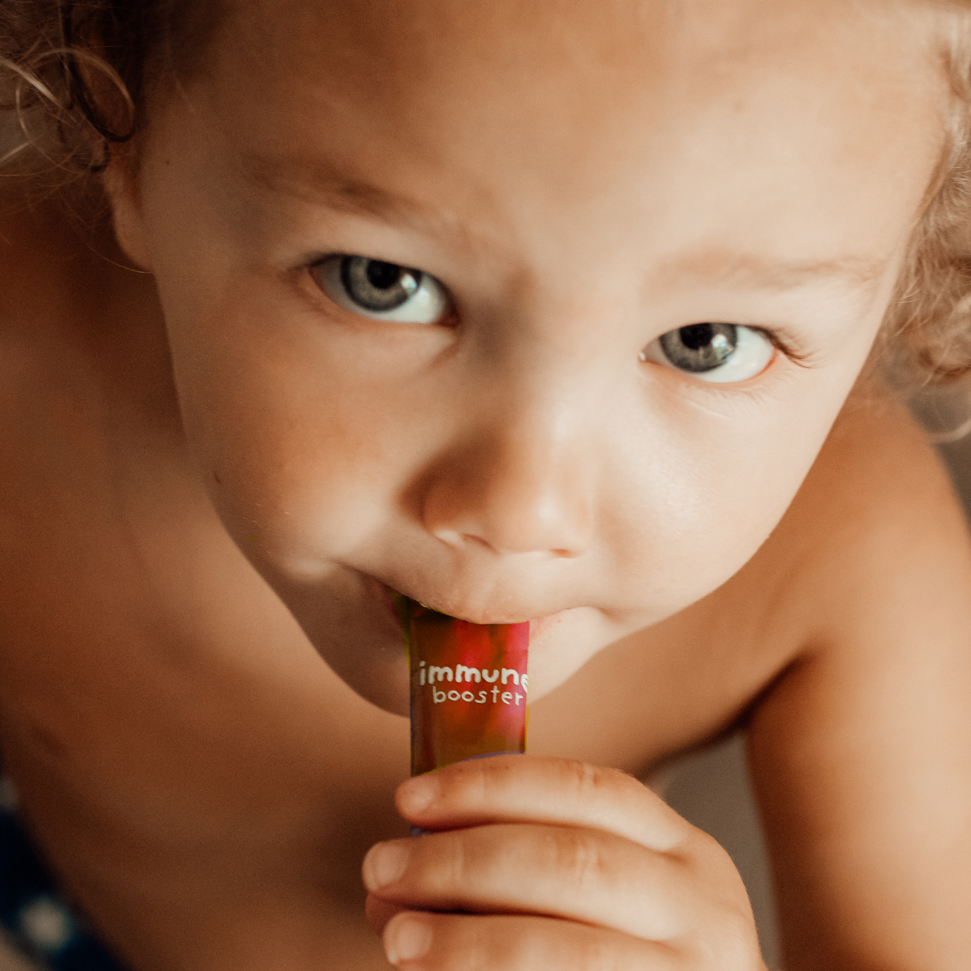 close up of a young child holding red stick pack of powder up to mouth